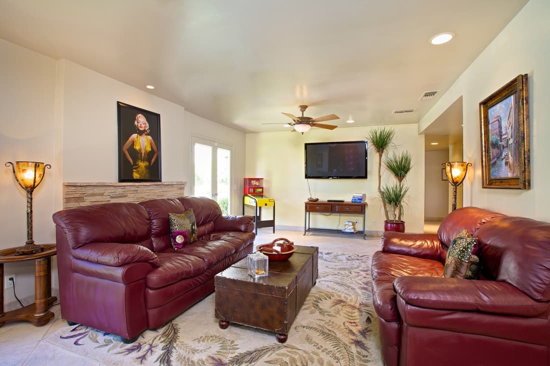 Living room with two dark red leather sofas, a trunk coffee table on a floral rug and a wall-mounted TV