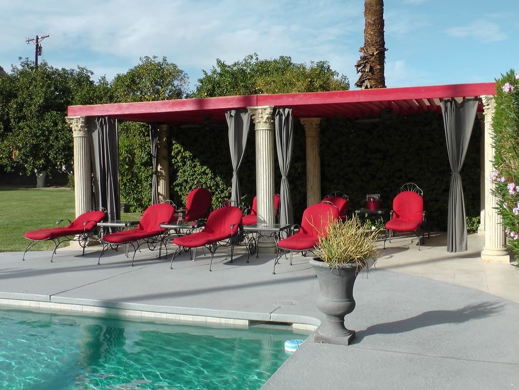 Poolside cabana with dark drapes and red loungers