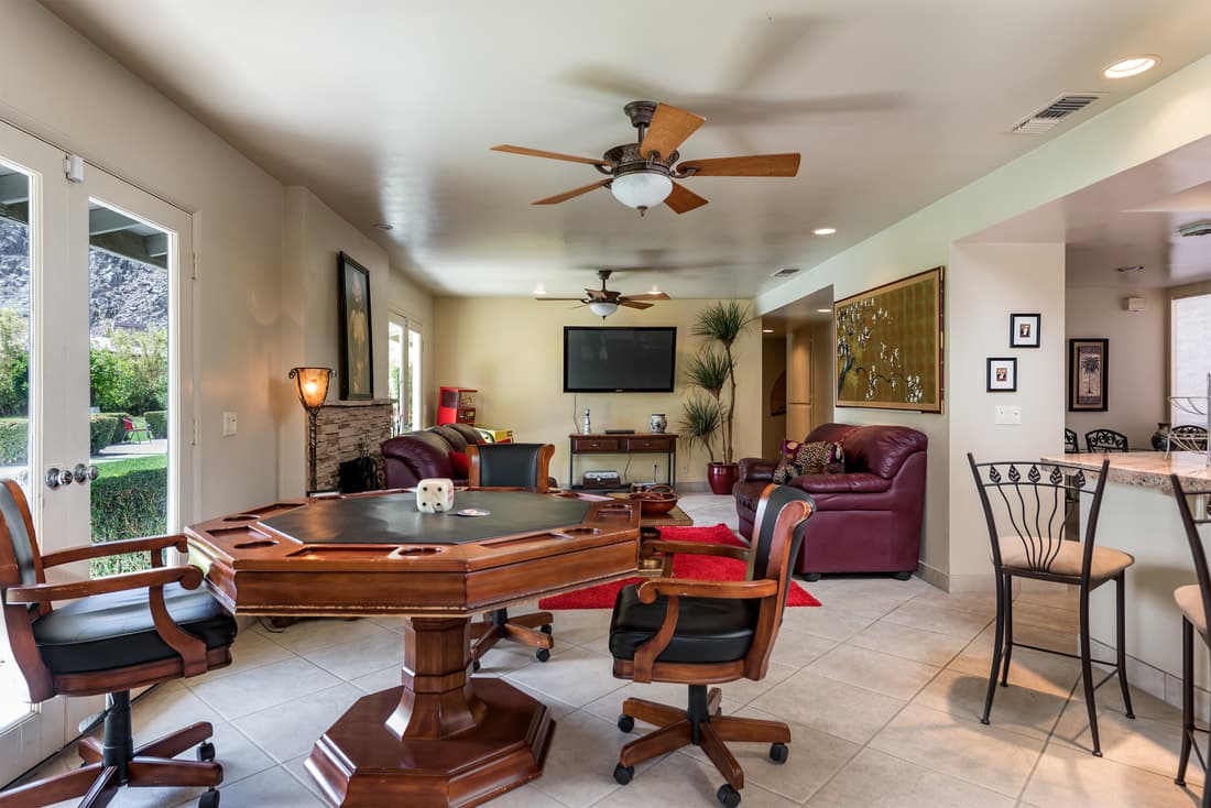 Octagonal wooden card table and chairs in a room opening toward the pool