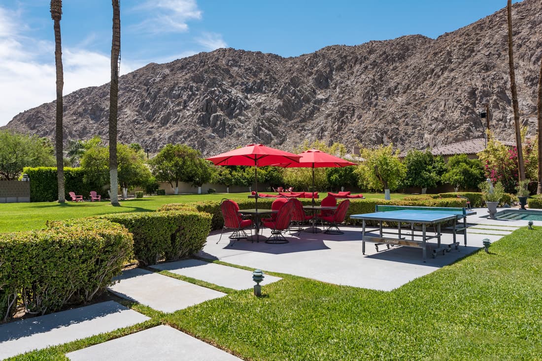 Mountain-facing patio with red umbrellas and lounge chairs
